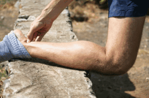Man with joint pain holding back of ankle