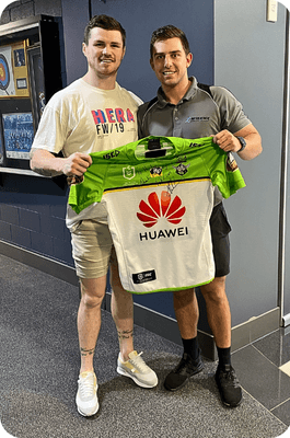 Two individuals holding a signed jersey.